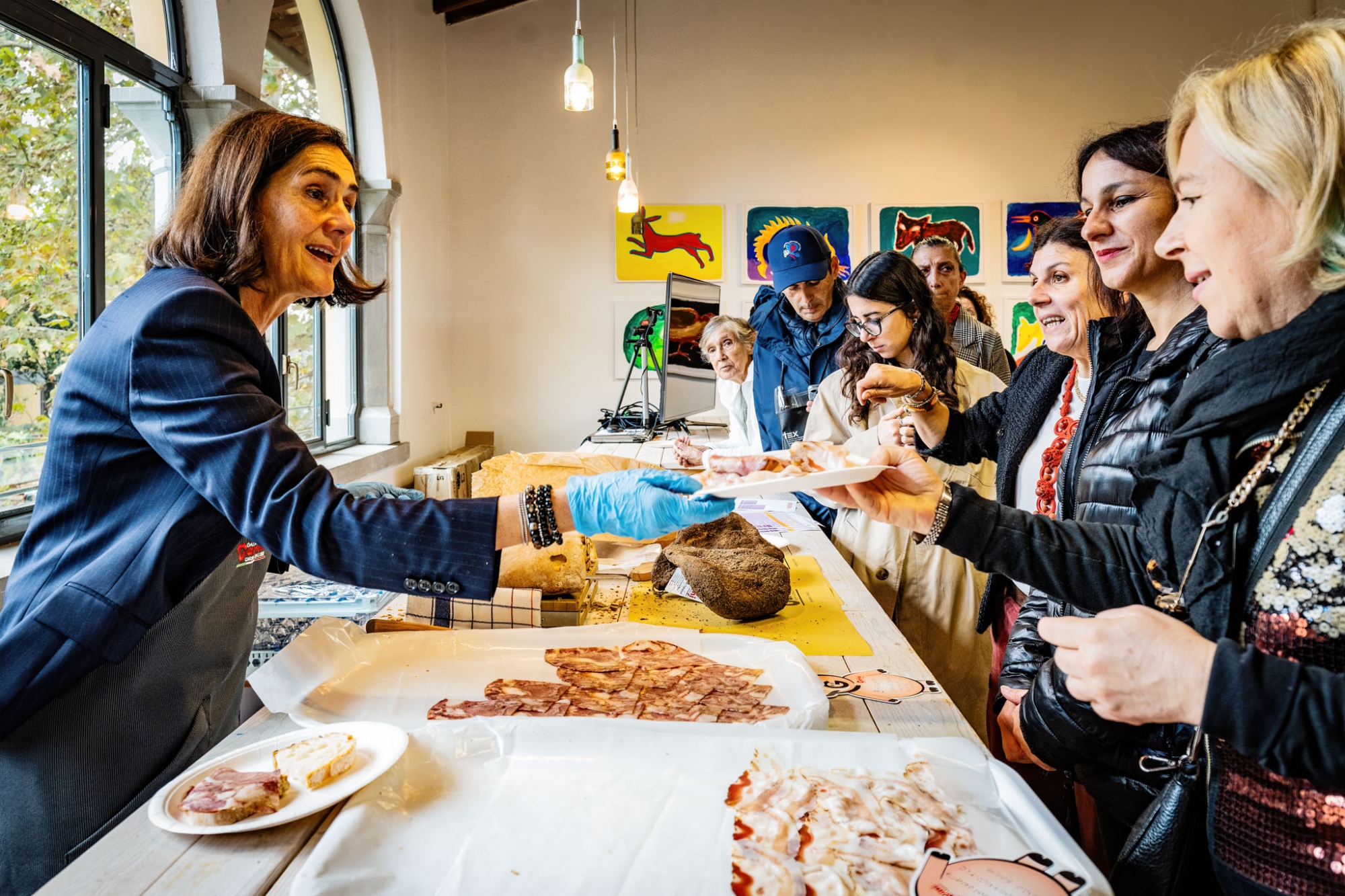 Degustazione di prodotti tipici toscani al Vecchio Conventino di Firenze, con visitatori e produttori intorno a un banco di assaggi.