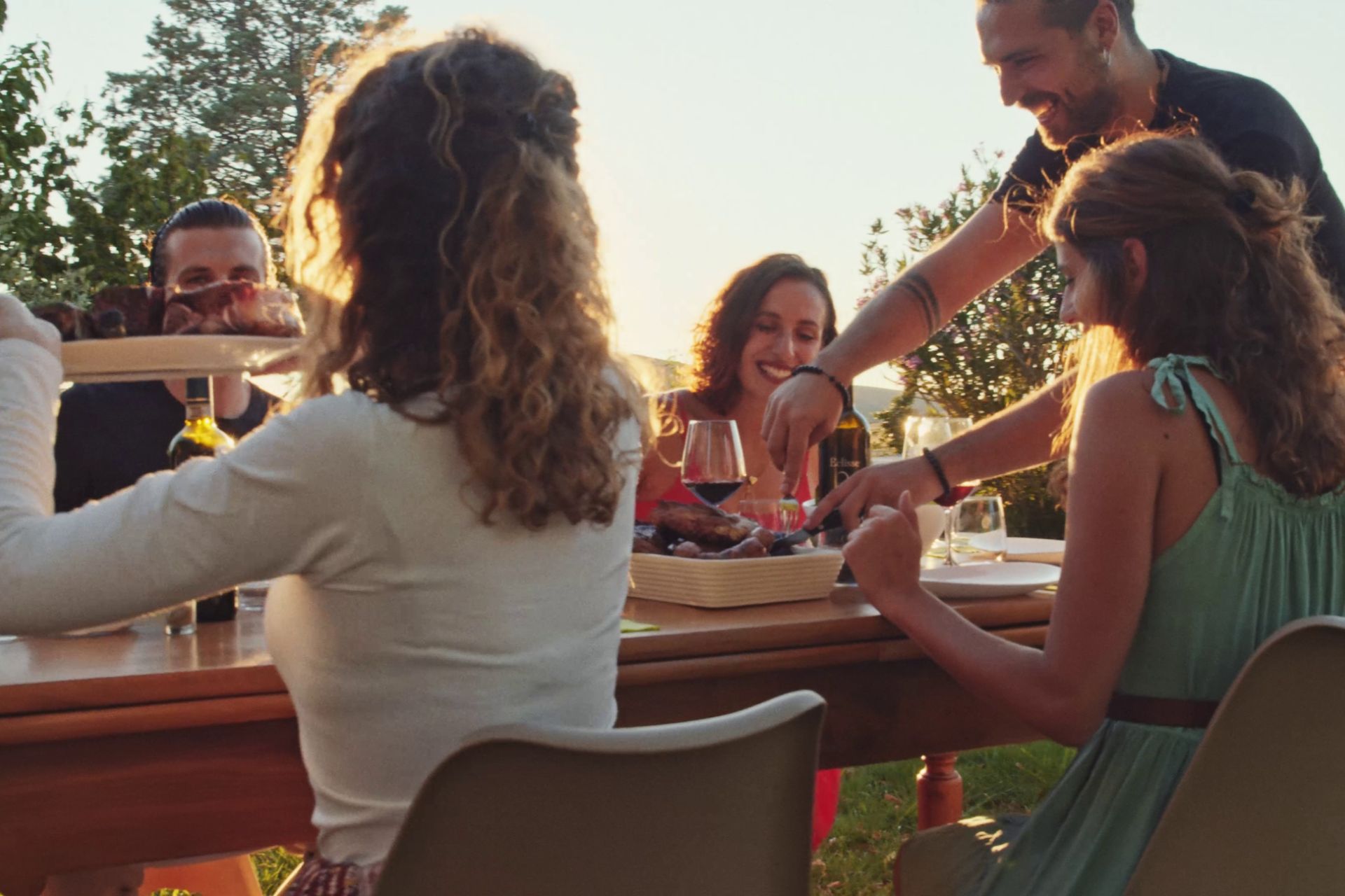 A group of people dining outdoors, eating Chianina beef and drinking wine