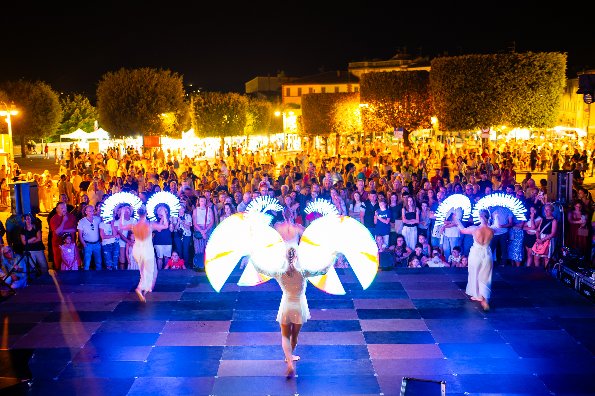 Immagine in notturna di una performance di teatro di strada con luci e costumi