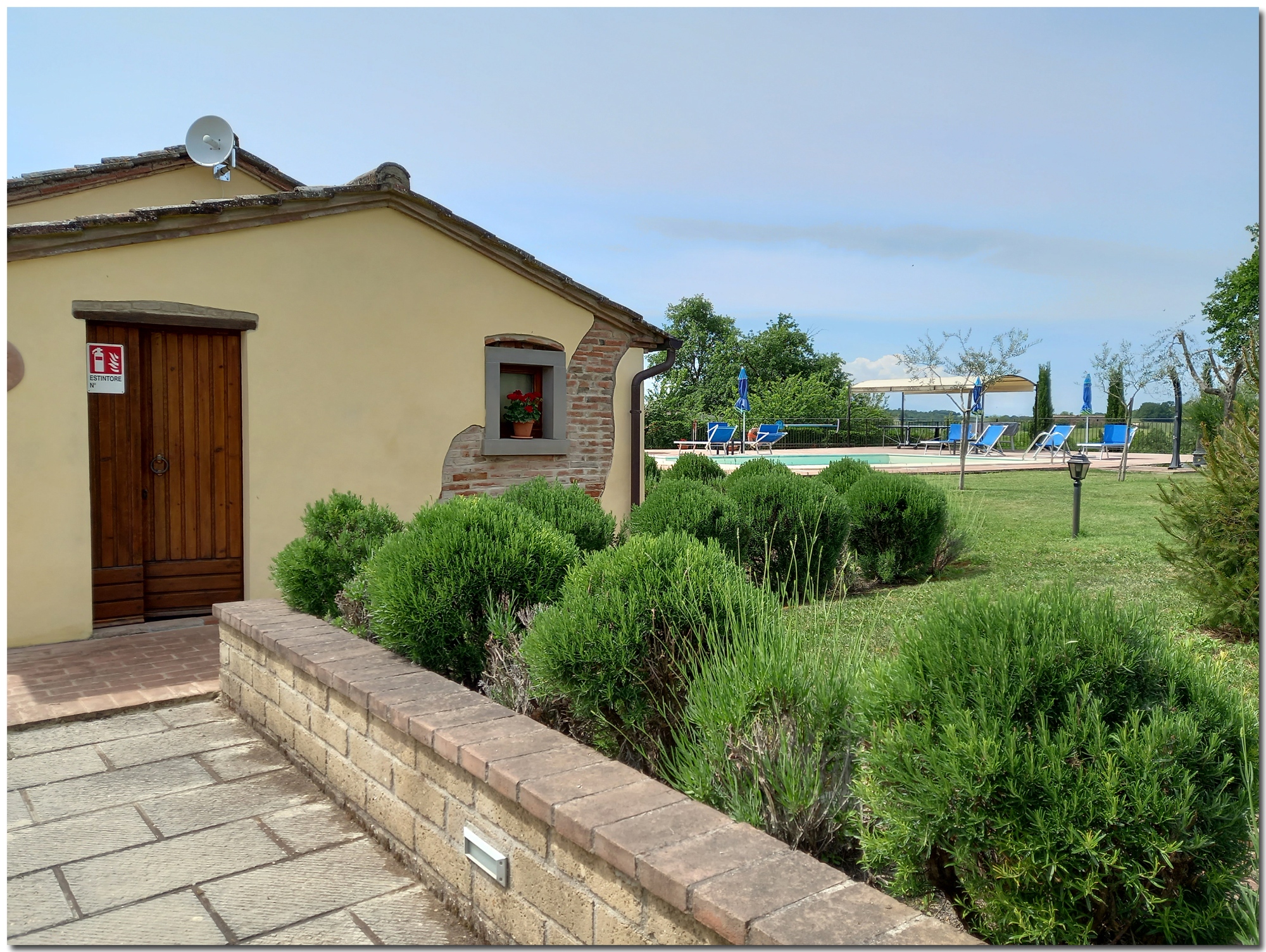 Manicured garden with rosemary bushes and pool view | Villino Cortona