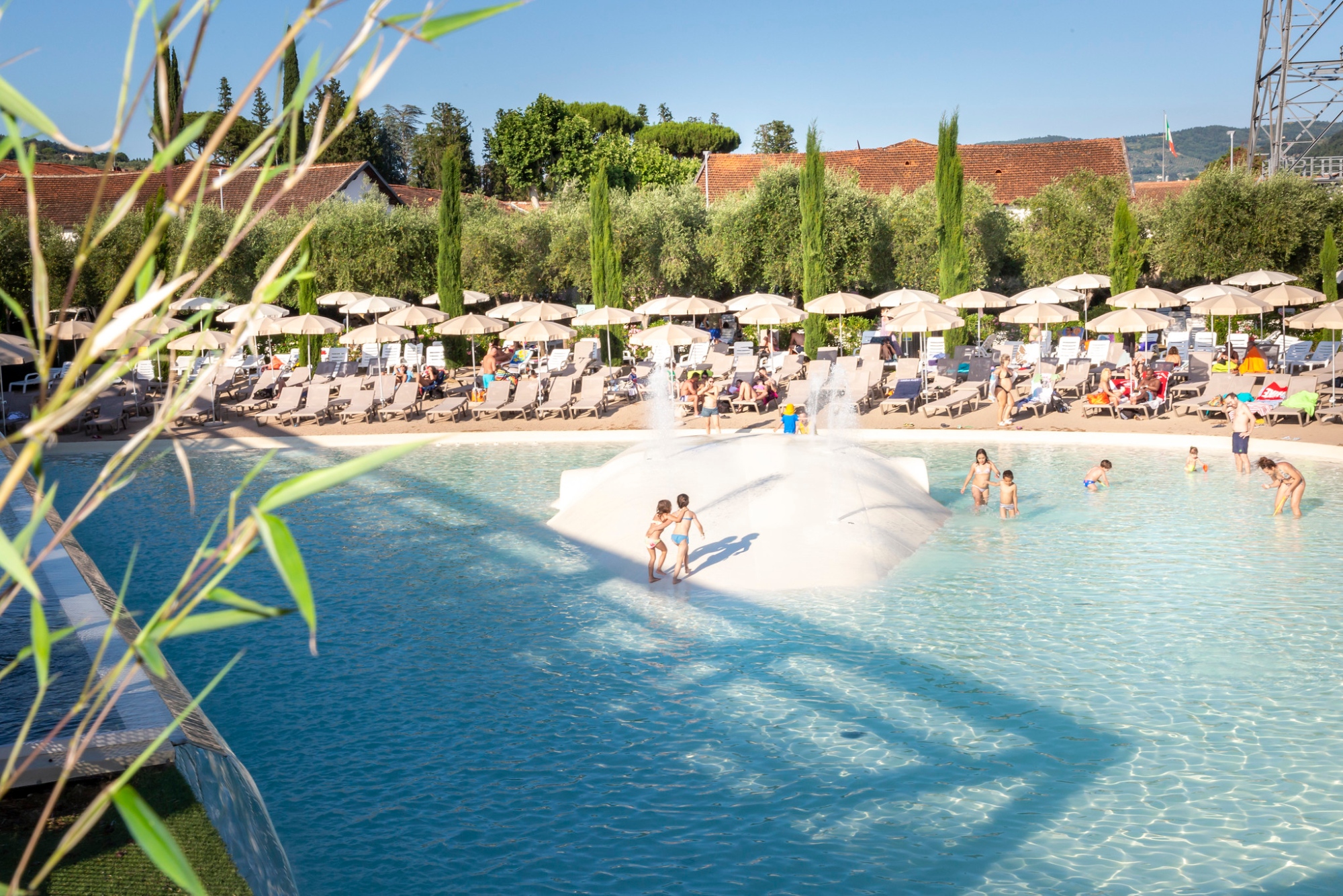 Panoramica di una piscina con bambini che giocano, ombrelloni e sedie ai lati
