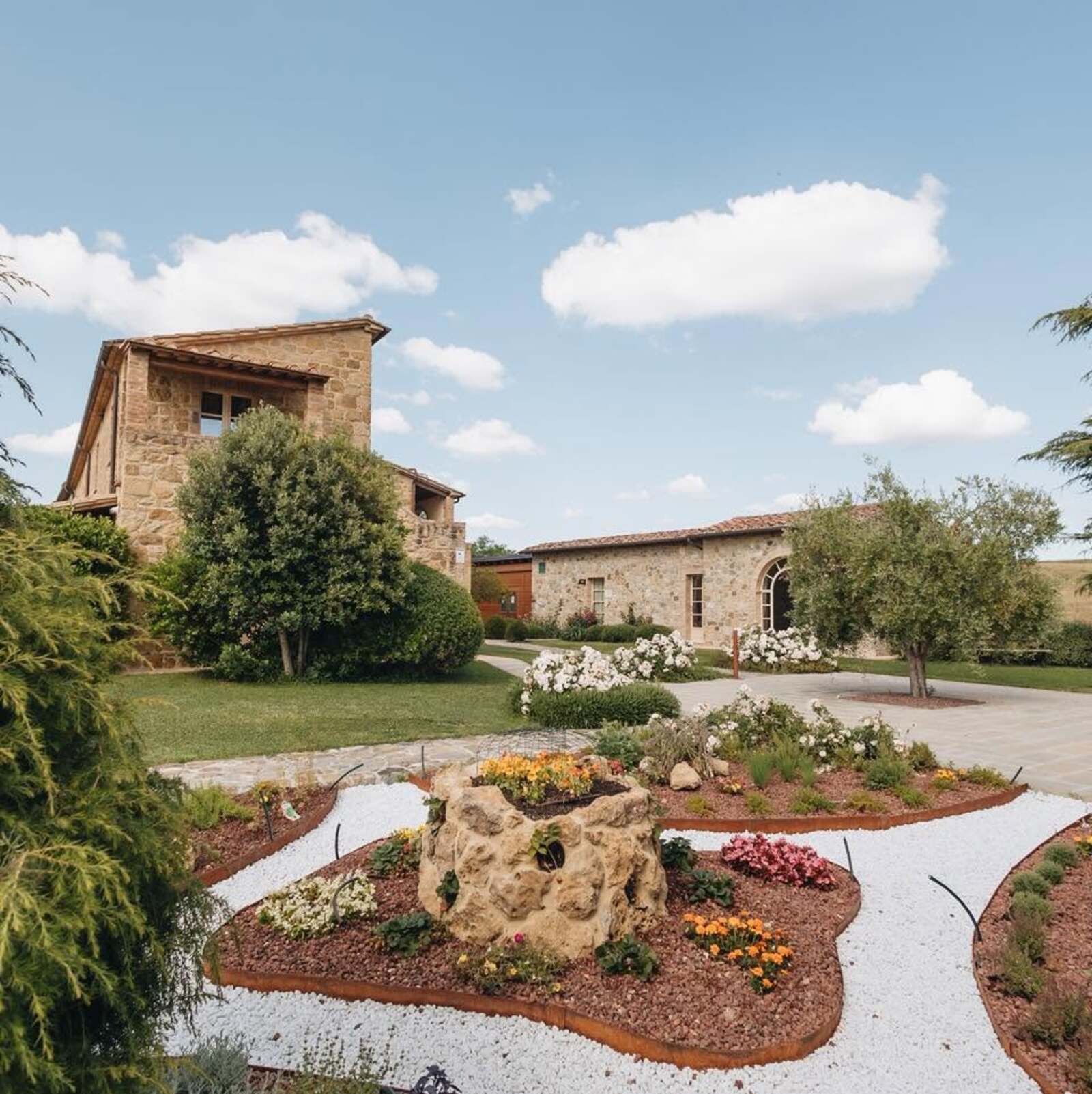 Flowered garden and stone farmhouses of a Tuscan estate | AGRITURISMO CAPANNA