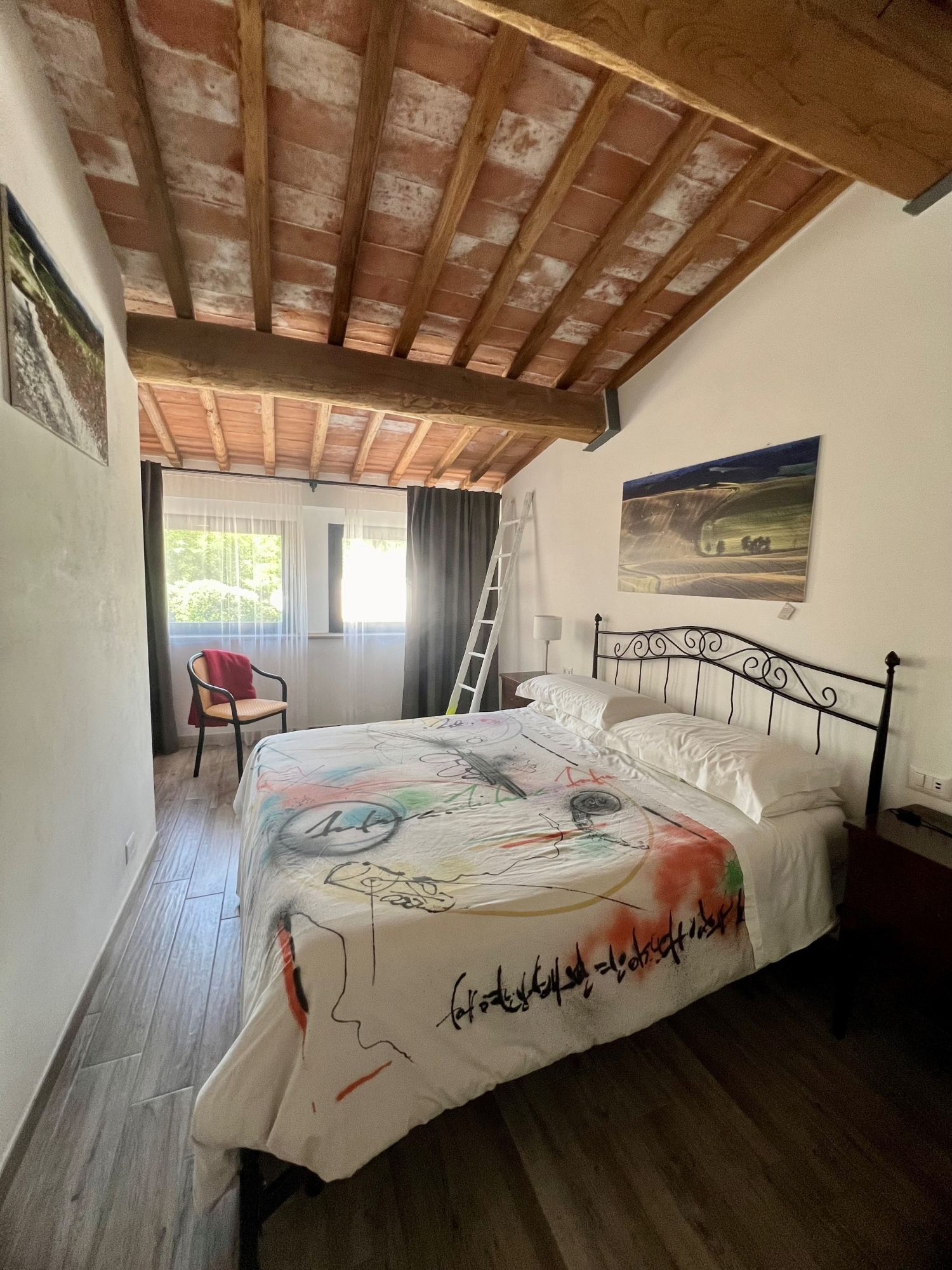 La camera dell'appartamento Ziro con due grandi finestre, travi a vista e struttura del letto in ferro