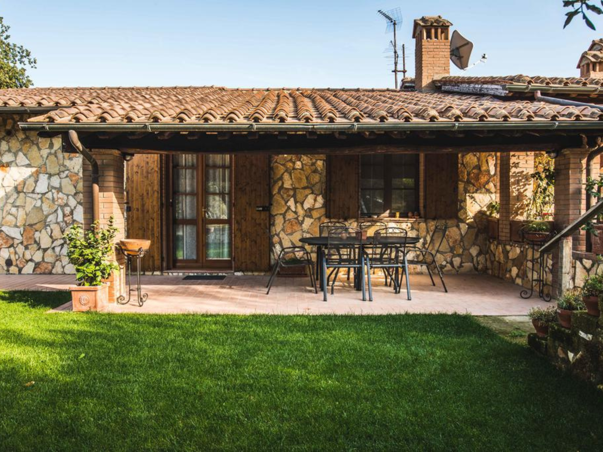 Lo spazio esterno attrezzato con tavoli e sedie e con giardino intorno alla struttura