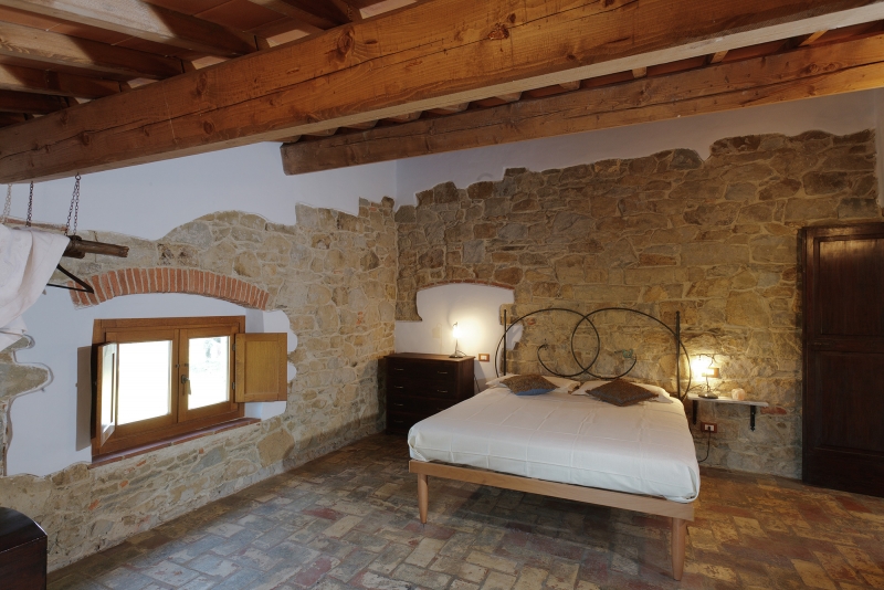 Una camera matrimoniale con lenzuola bianche all'Agriturismo Poderaccio
