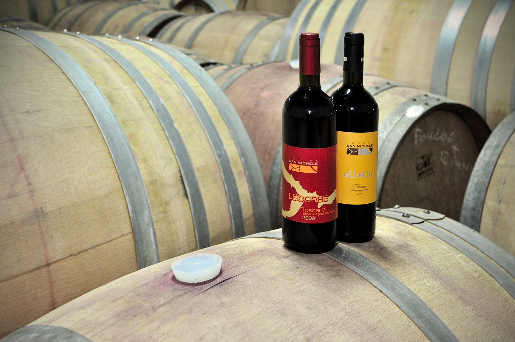 Due bottiglie di vino rosso in piedi su una botte di vino in legno chiaro
