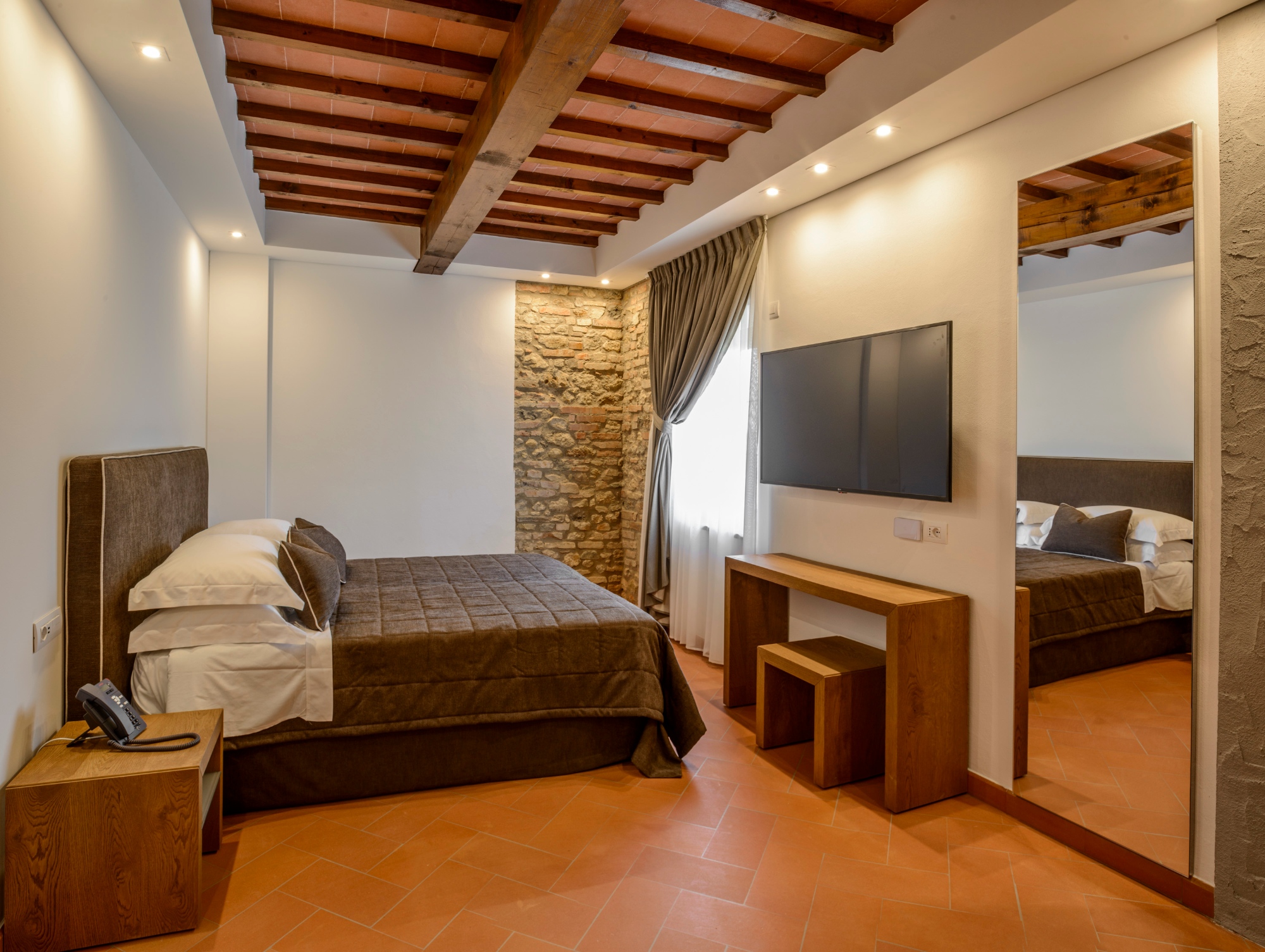 Il letto di una camera matrimoniale con soffitto con travi a vista