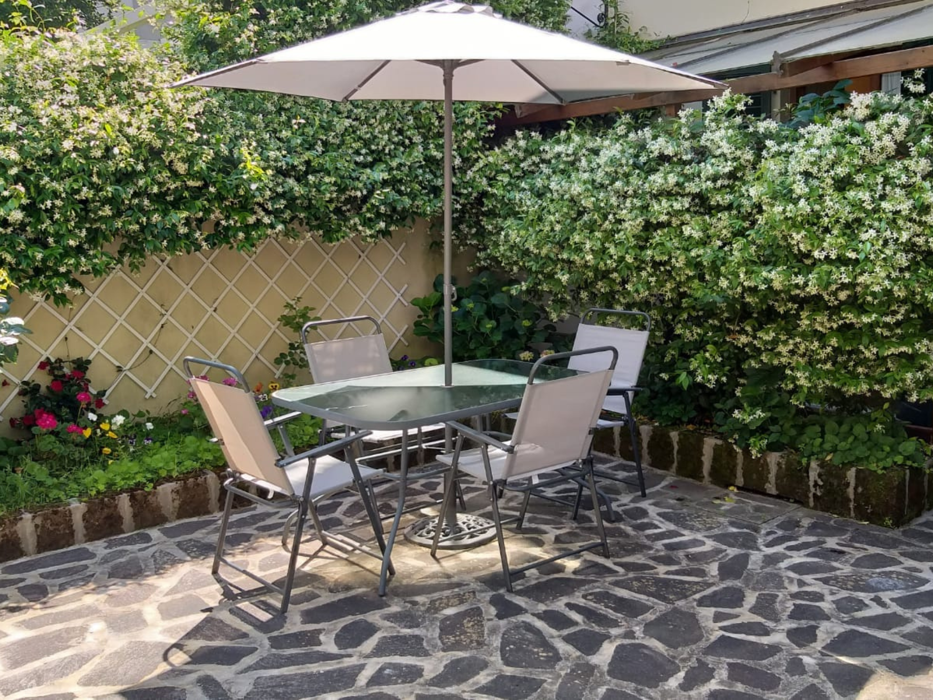 Casa Vacanze Le Rose di Leo angolo giardino con tavolino obrellone e sedie