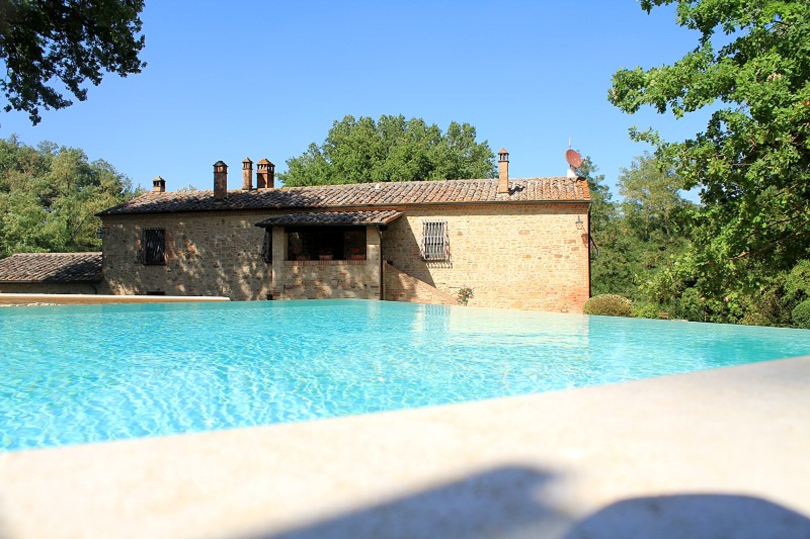 Piscina panoramica all'aperto di un casale in pietra a Montepulciano