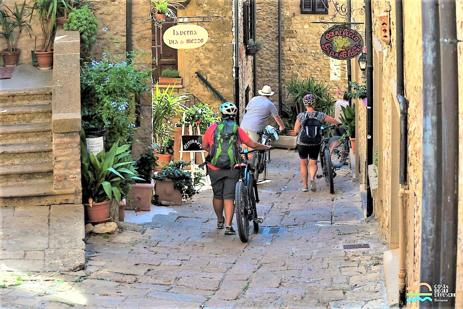 Turisti in bici in in borgo della Costa degli Etruschi