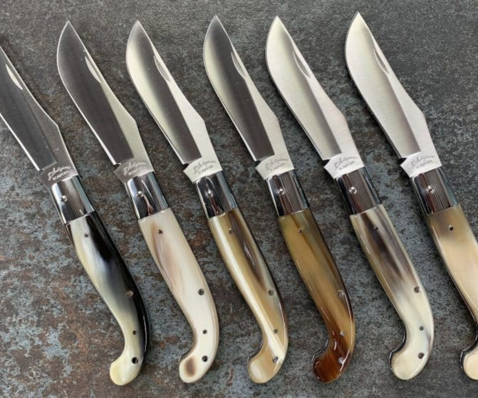 Handcrafted knives from Scarperia displayed on a stone surface