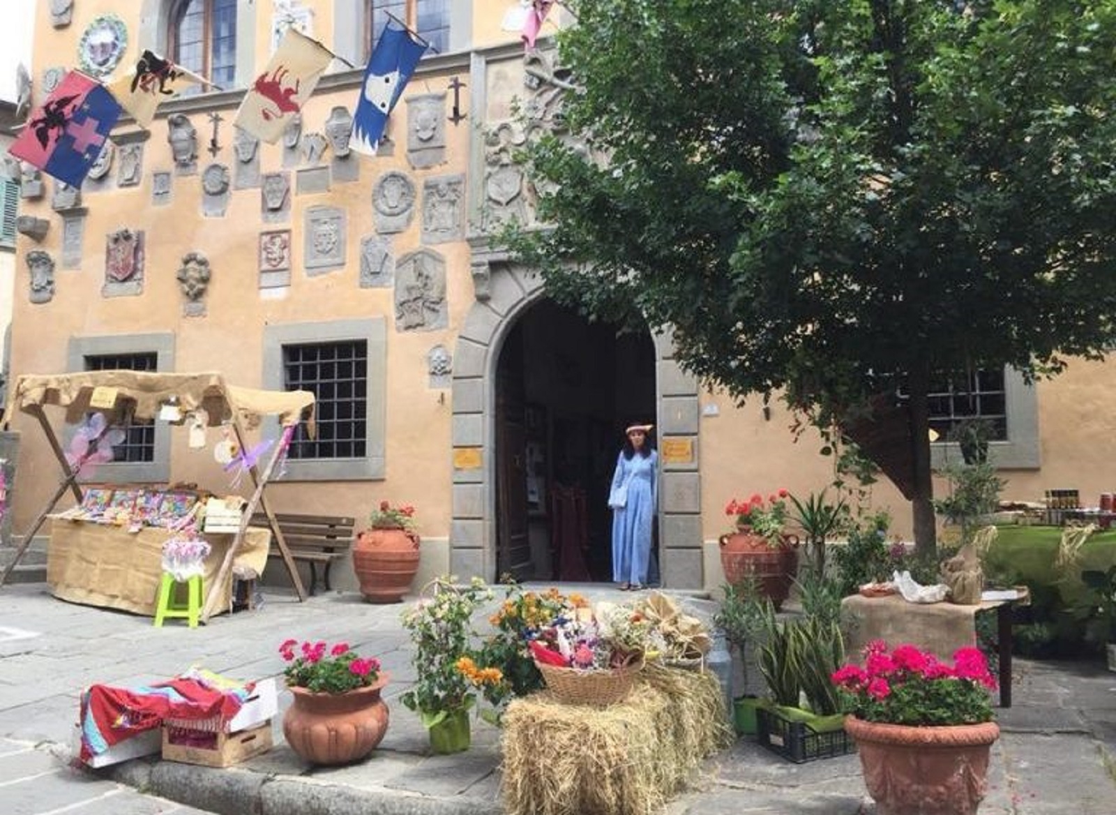 Dekoration bei Cutigliano Medievale in der Altstadt mit einem Handwerksstand, Blumenschmuck und einer Darstellerin in historischem Gewand