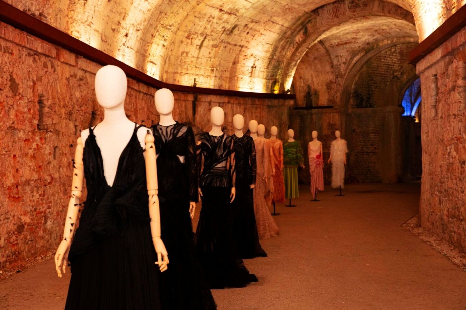 10 manichini con abiti da sera eleganti disposti in fila nel sotterraneo delle Mura di Lucca