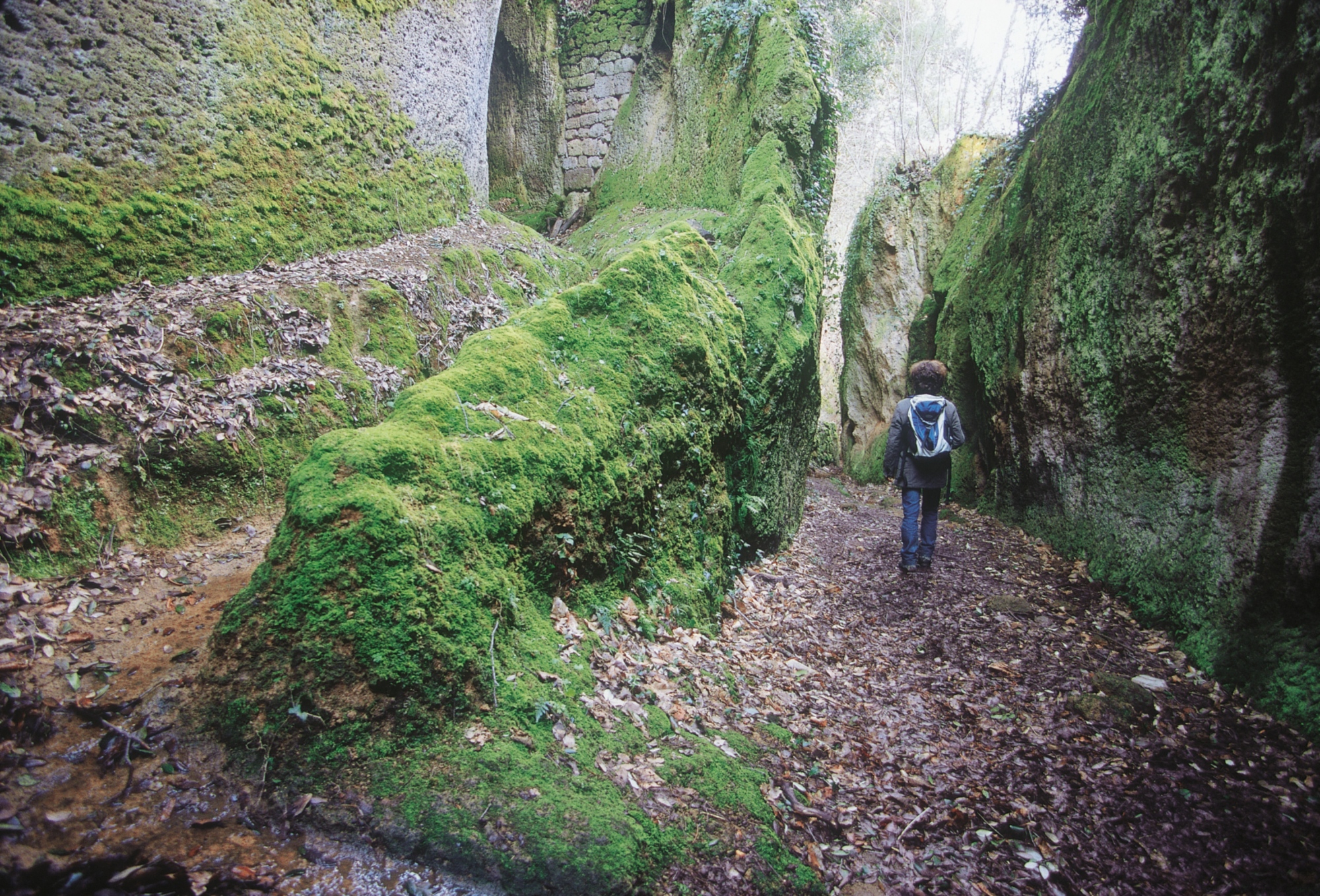 Randonneur muni d’un sac à dos marchant au fond d’une gorge profonde et étroite creusée dans la roche