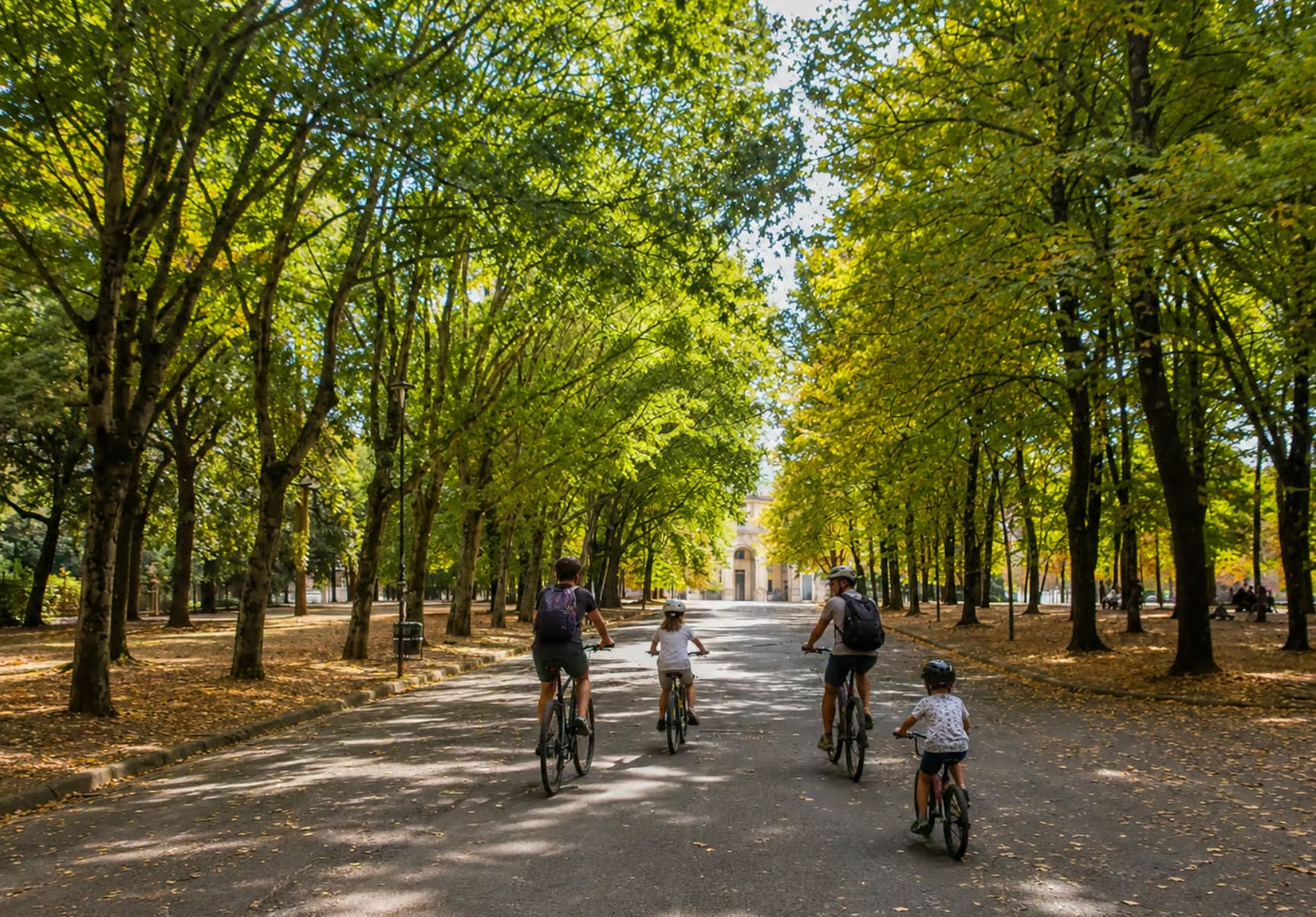 Family cycling in a tree-lined park in Florence