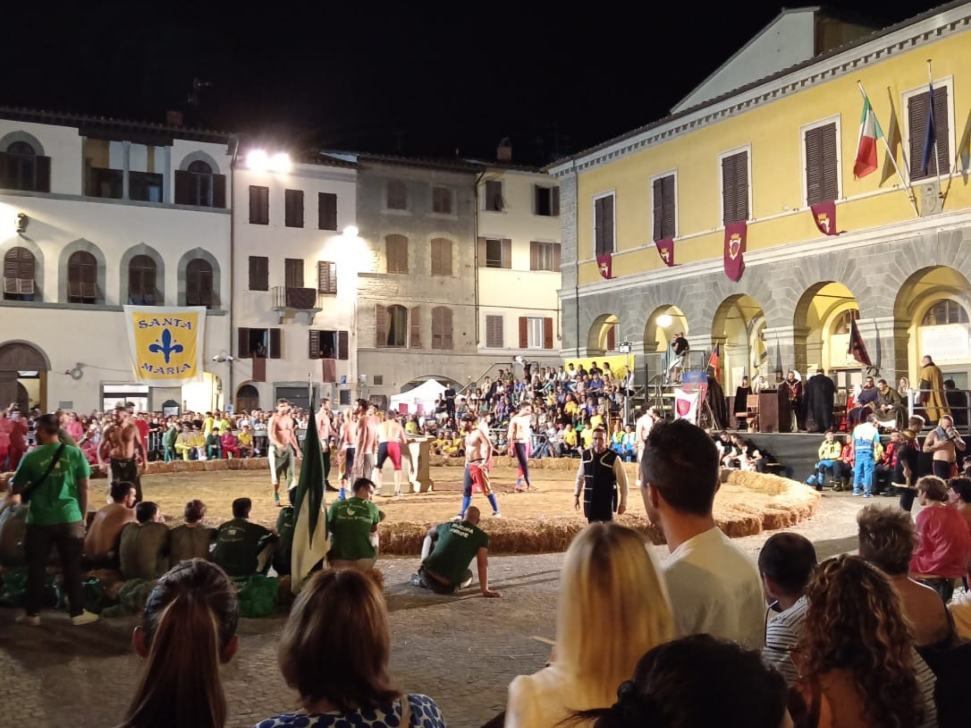 Spettatori in Piazza Varchi assistono in notturna al tradizionale Gioco del Pozzo.