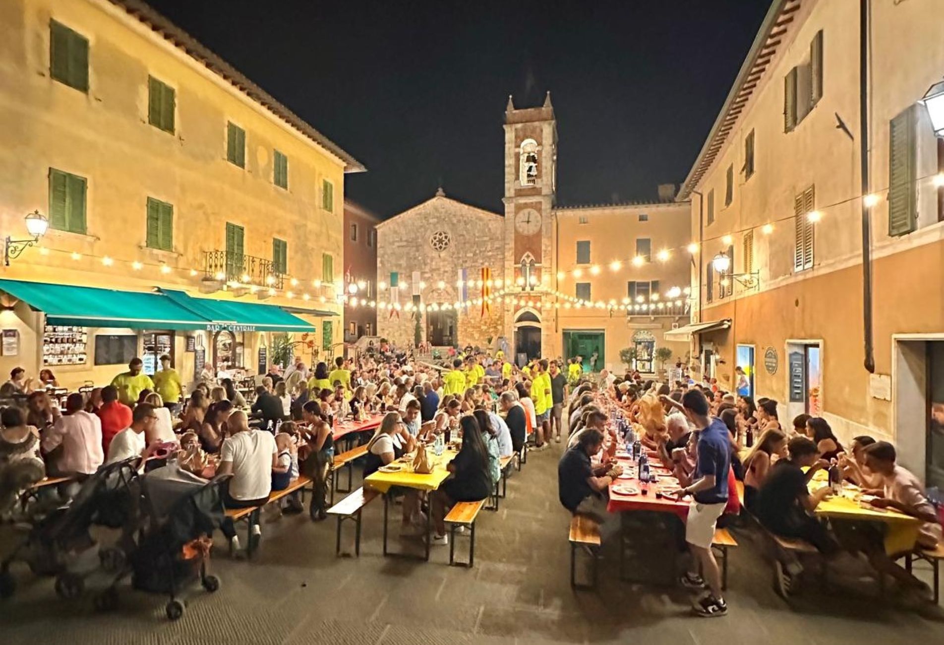 Tavolate in piazza con persone che mangiano a cena