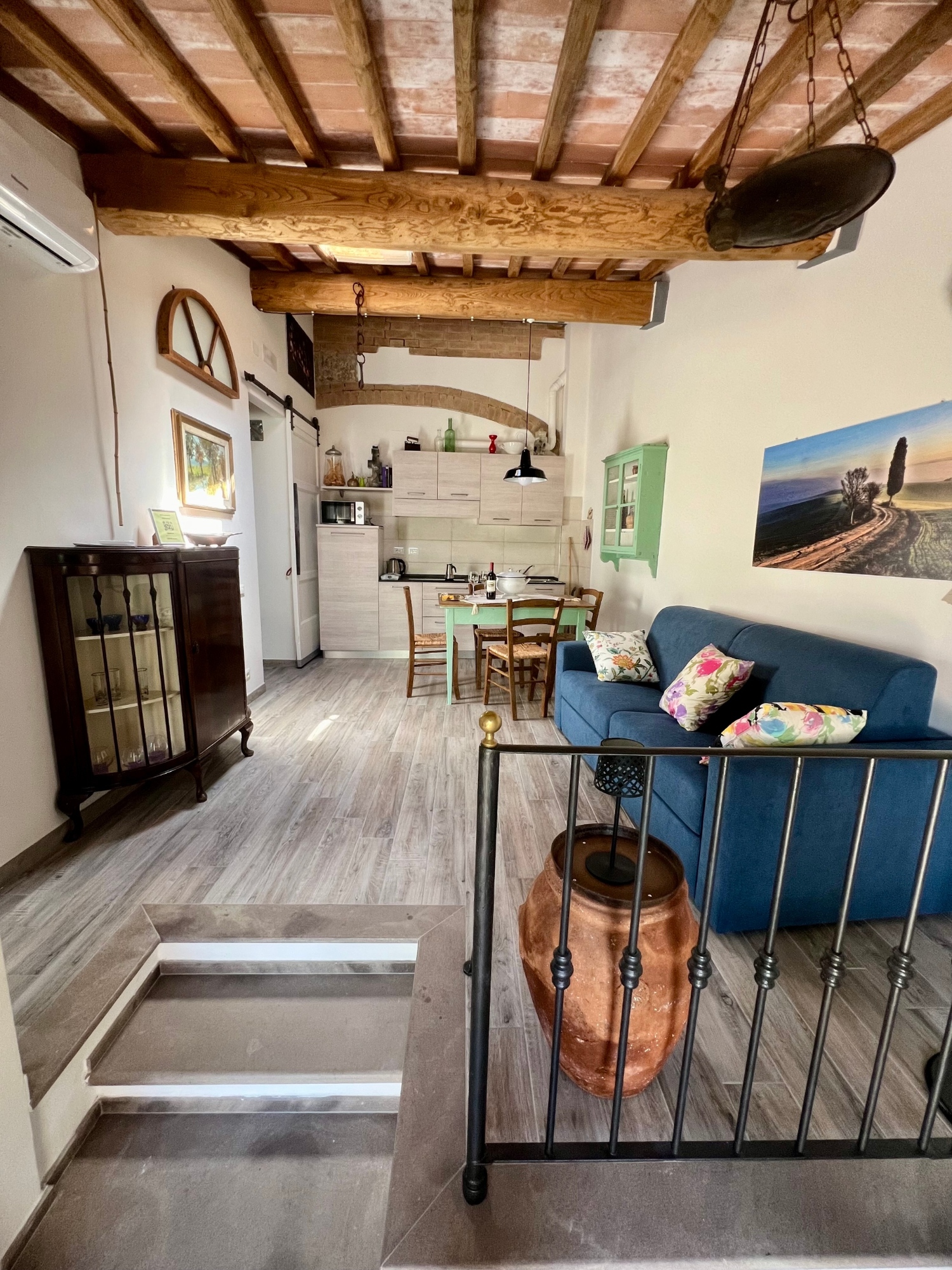 La cucina soggiorno degli Appartamenti Ziro con scale all'ingresso e soffitto con travi a vista