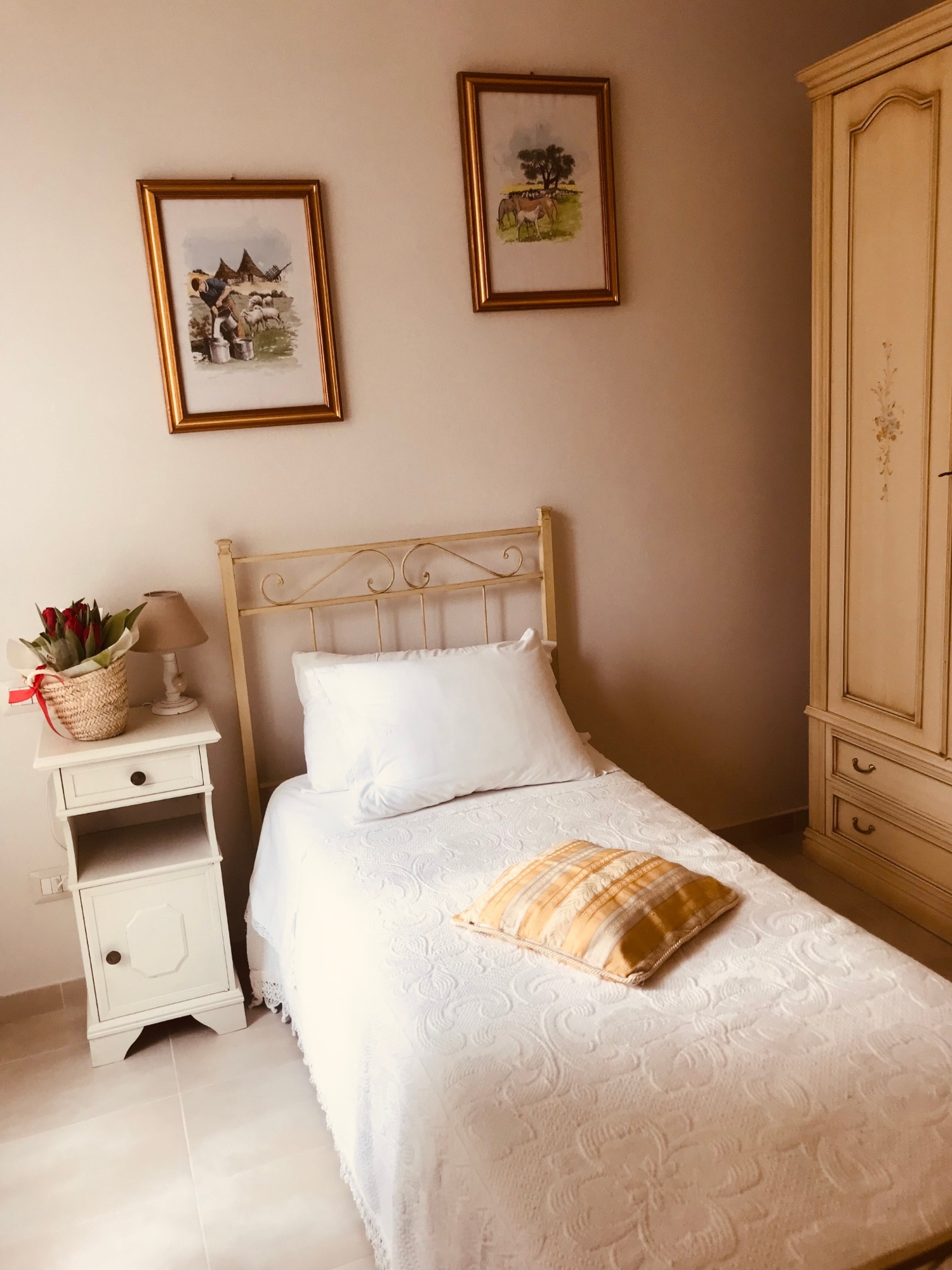 Un letto singolo con lenzuola bianche e mobilio in stile rustico