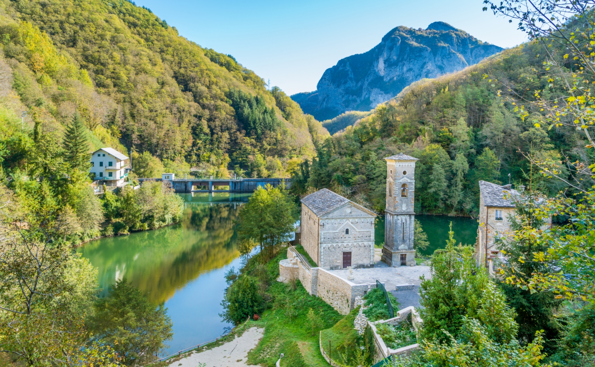 Vista dall'alto di Isola Santa, piccola frazione affacciata su un lago e circondata dalle montagne.