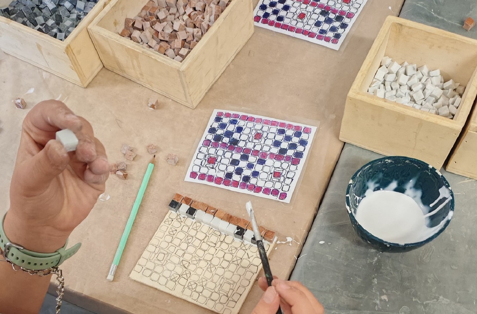 Immagine di mani che incollano tesserine di un mosaico