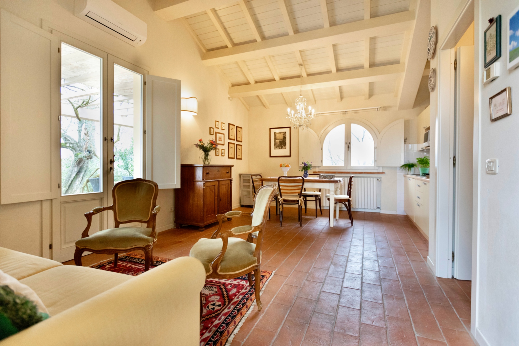 La sala di un appartamento con pavimento in cotto e travi a vista, l'arredamento è in stile classico
