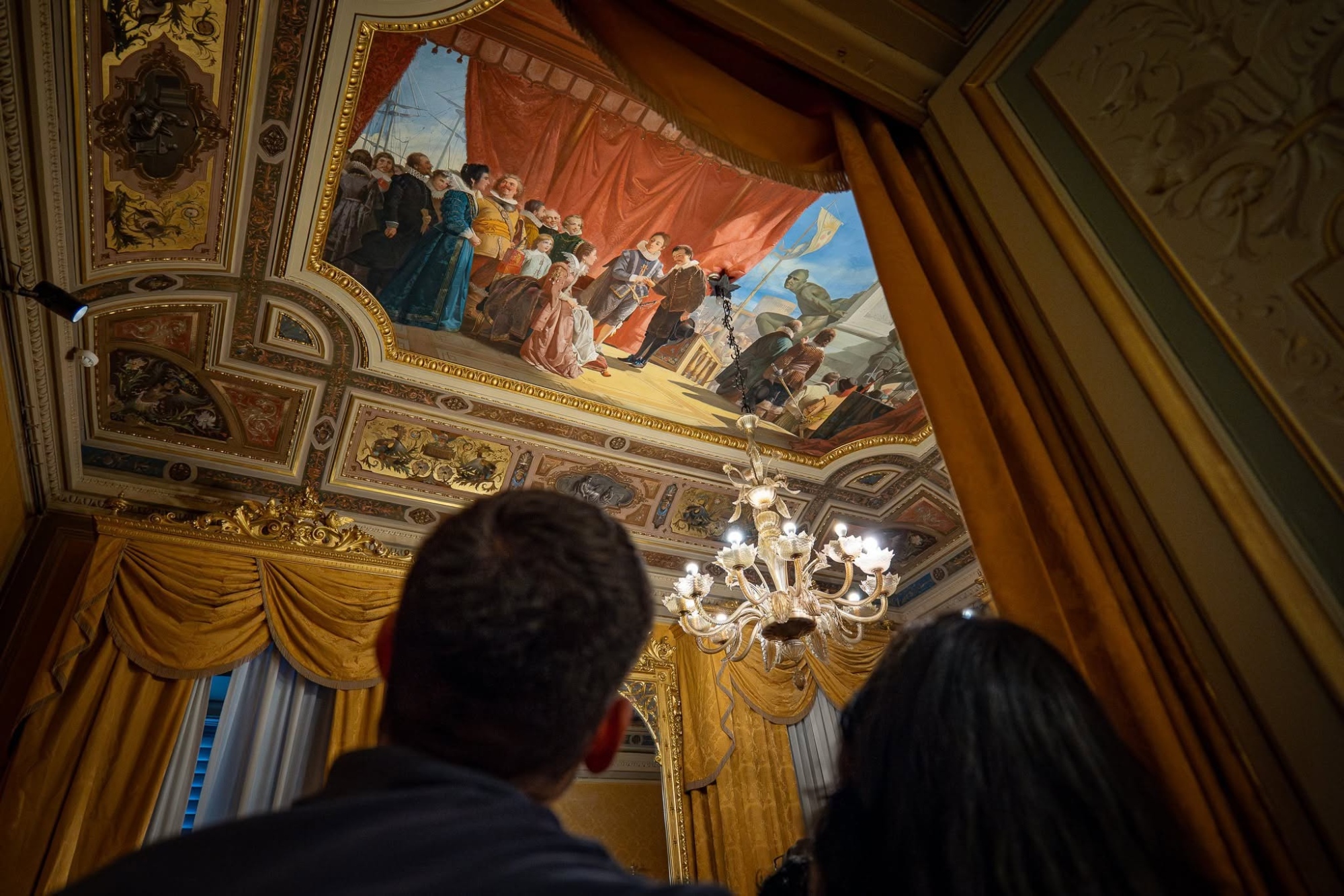 Due visitatori osservano il soffitto affrescato e riccamente decorato di una sala del Museo Civico Giovanni Fattori di Livorno.