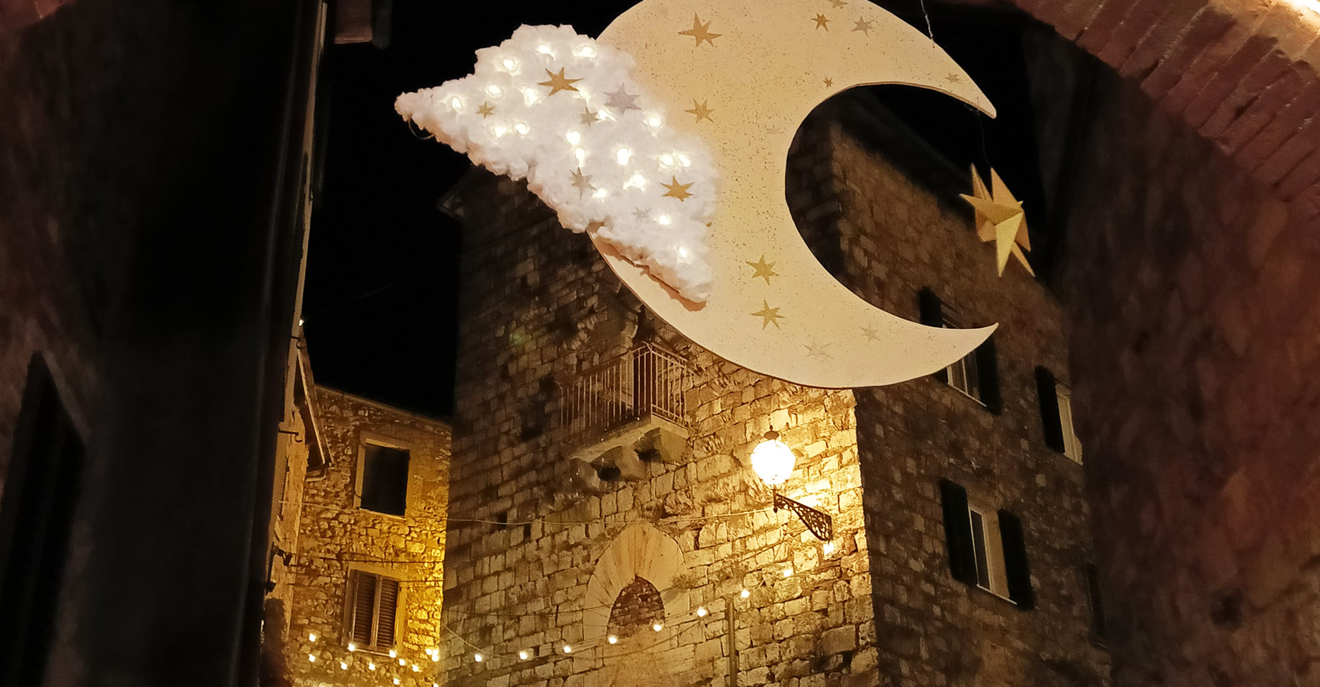 Immagine diel borgo con la riproduzione di una grande luna appesa fra i palazzi