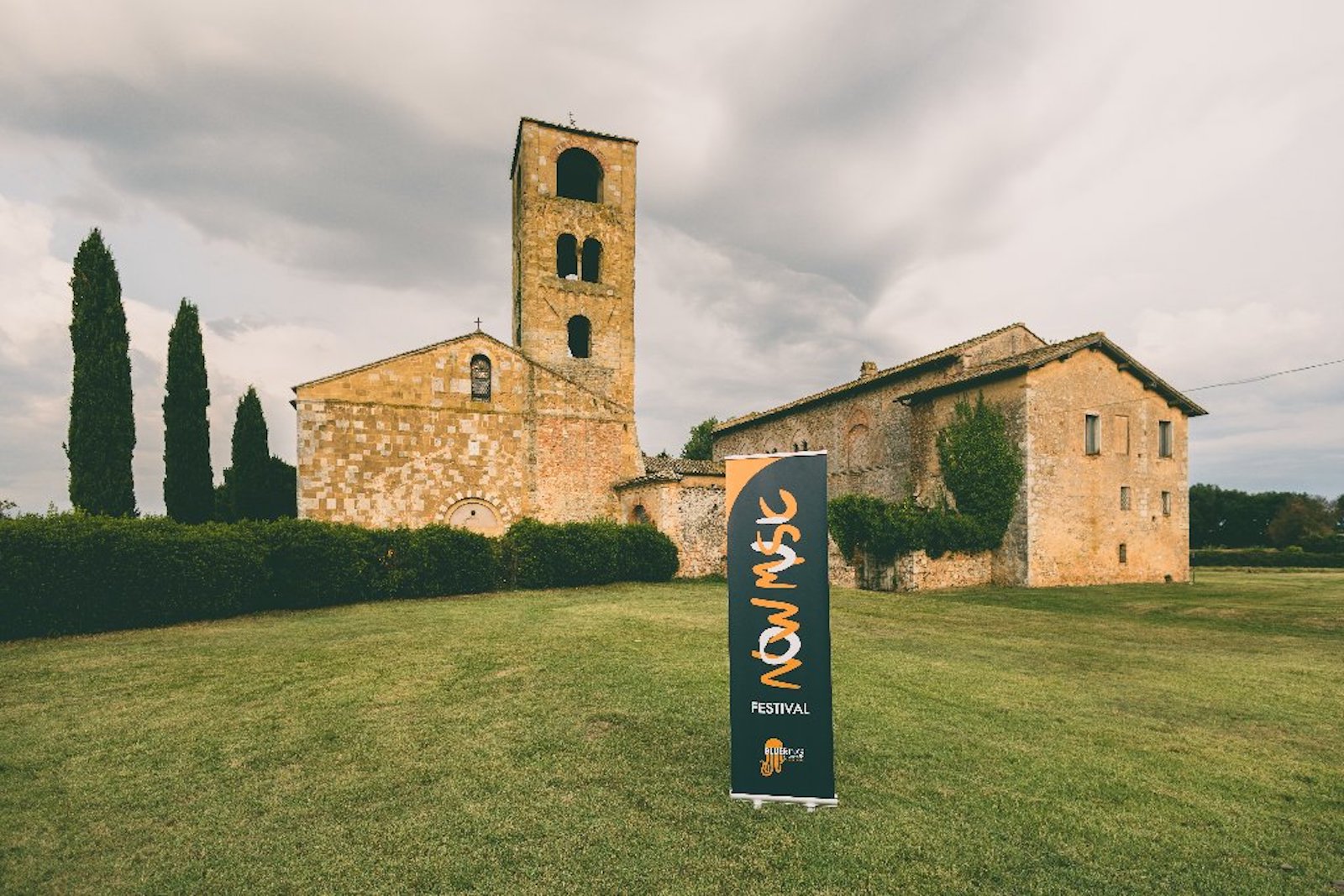La Pieve di San Giovanni Battista a Ponte allo Spino, sede del Now Music Festival, con il pannello della manifestazione in primo piano.