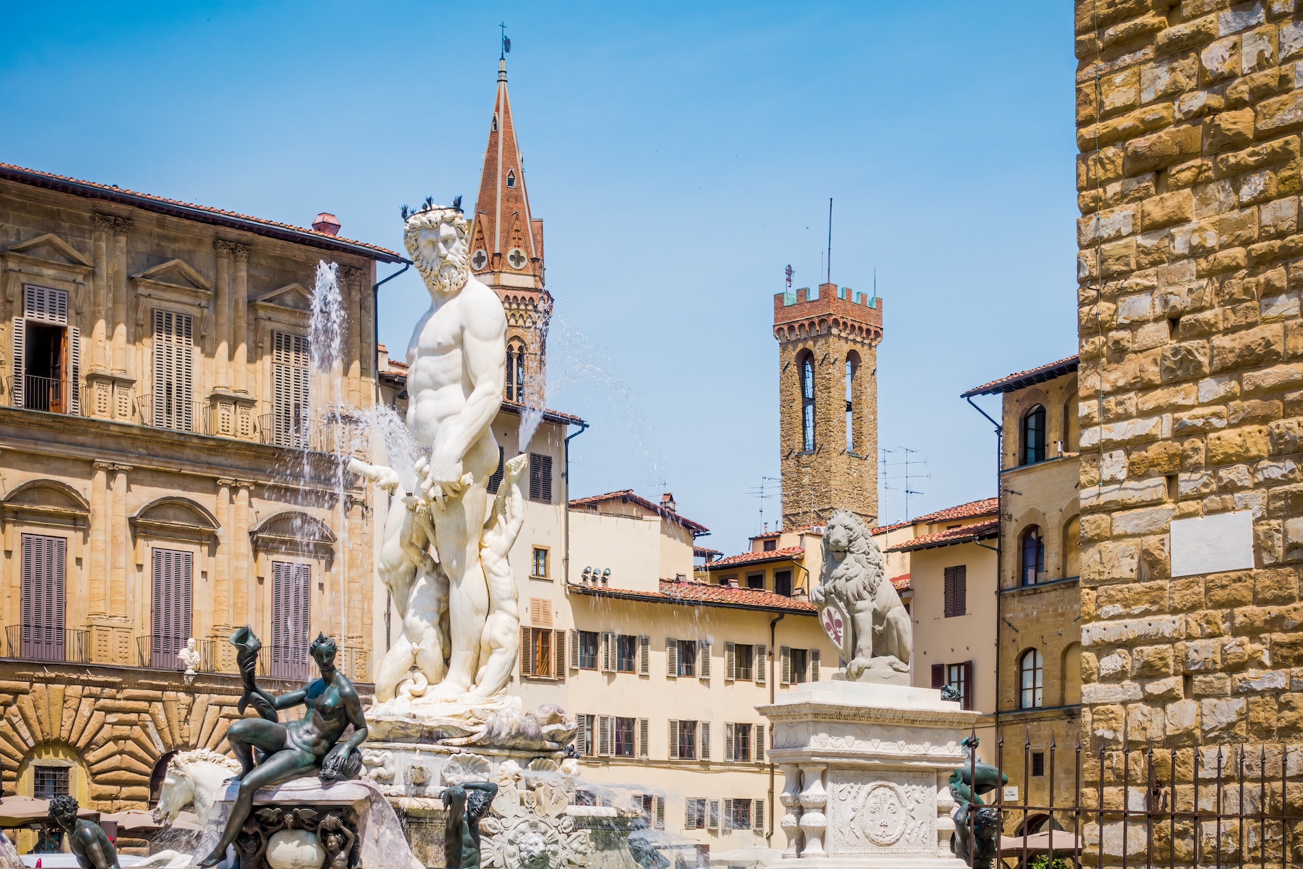 La maestosa statua in marmo bianco del Nettuno nell'omonima fontana di Piazza della Signoria a Firenze, circondata da zampilli d'acqua, sculture in bronzo e palazzi storici