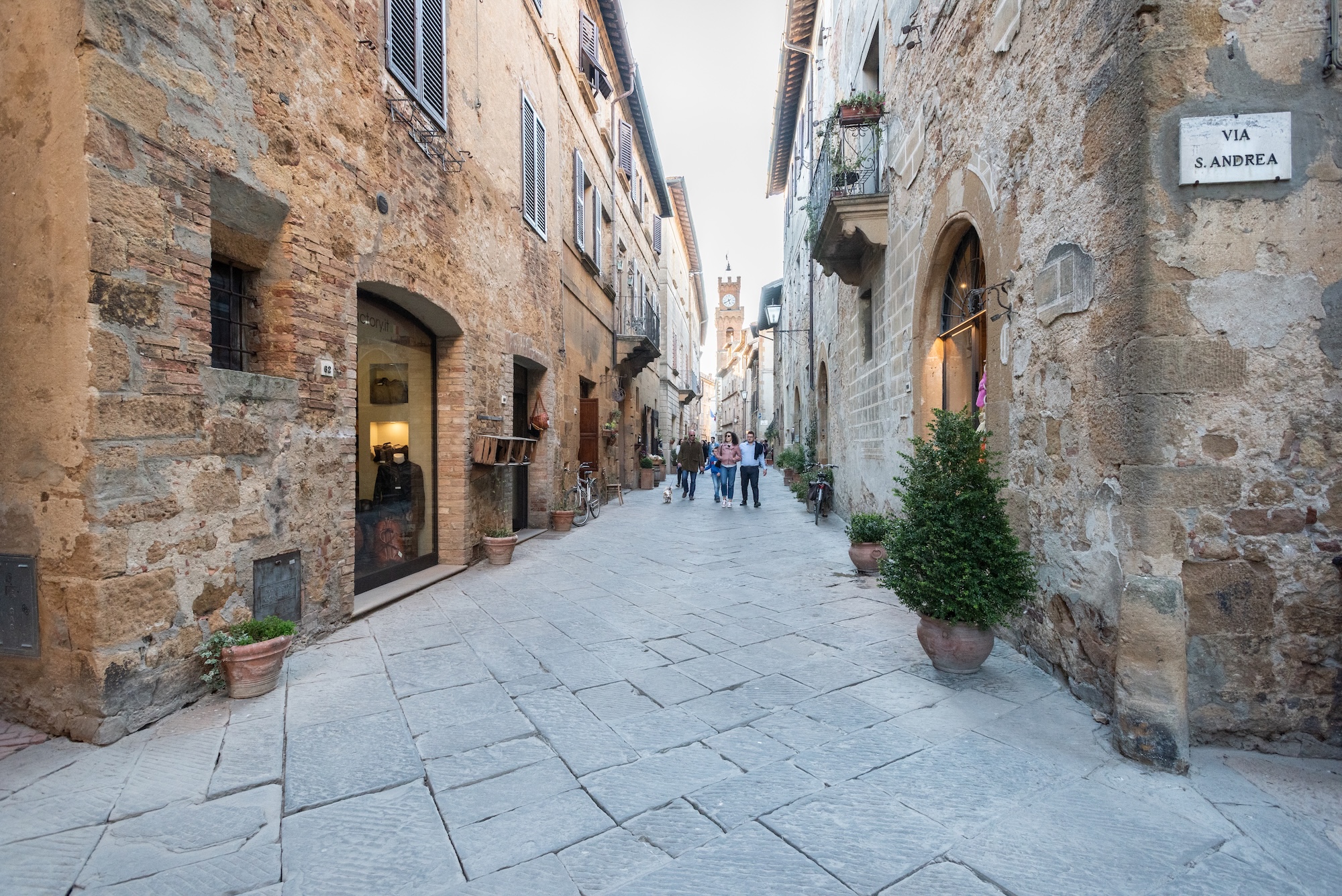 Una caratteristica strada pedonale lastricata a Pienza fiancheggiata da antichi edifici storici in pietra e mattoni