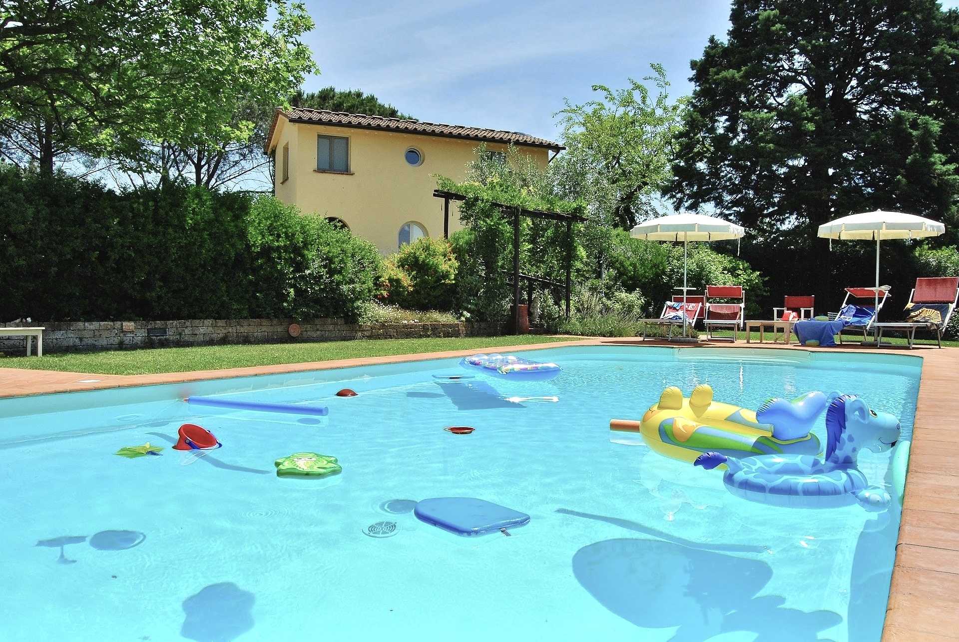La piscina di Villa Quieta con gonfiabili e circondata da piante