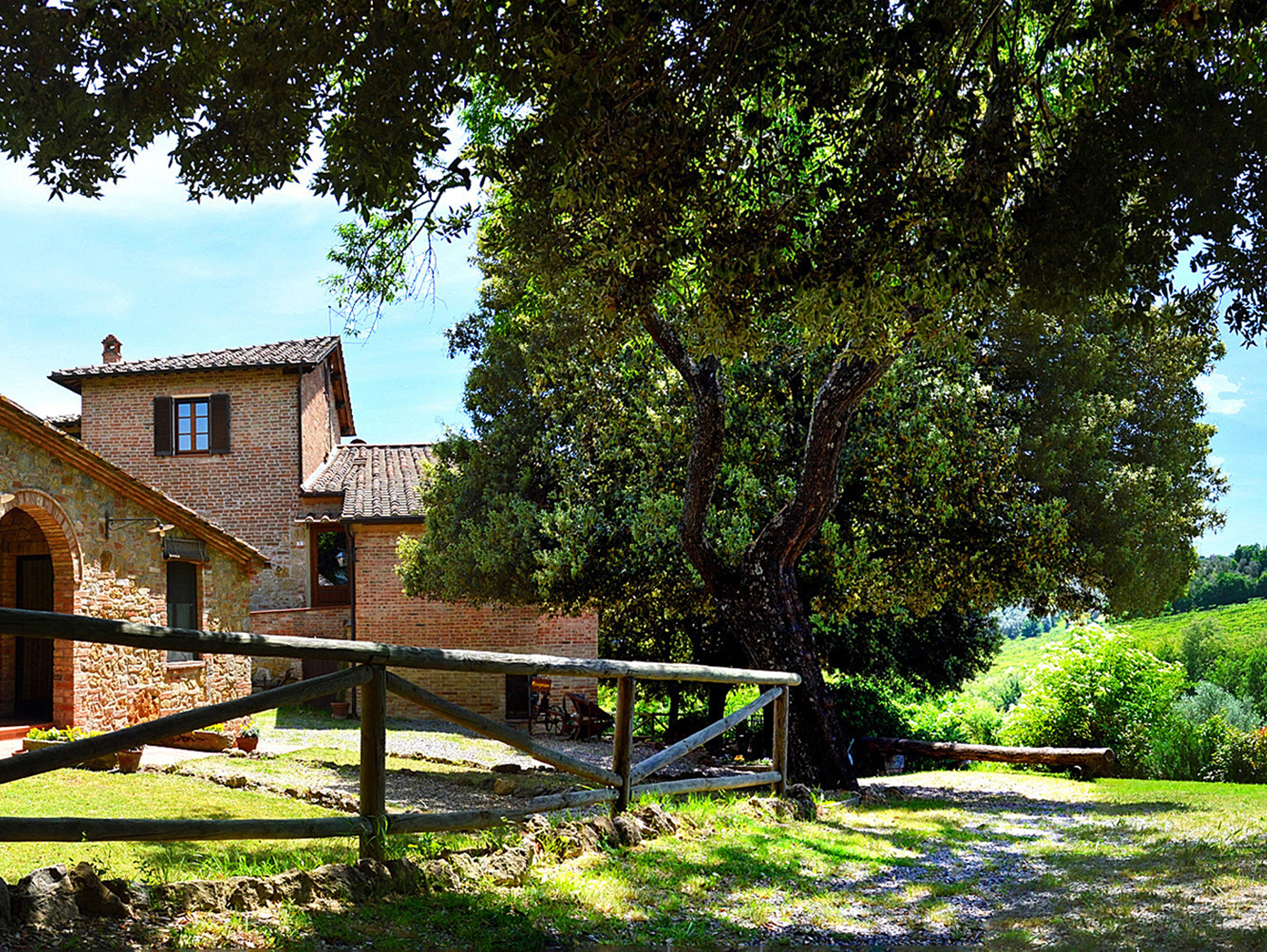 Esterno del casale in pietra circondato da alberi e campagna vicino a Montepulciano
