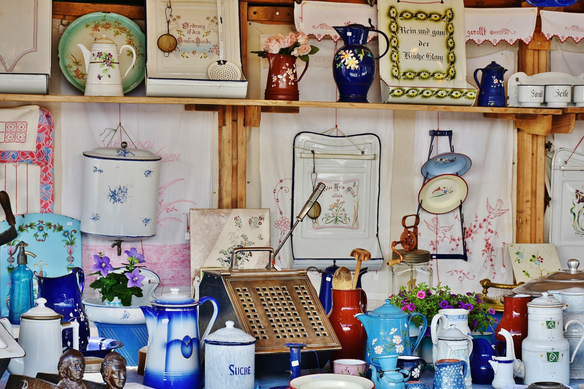 Oggetti vintage e accessori per la casa esposti su scaffali, tra brocche smaltate, contenitori decorati e utensili d’epoca.