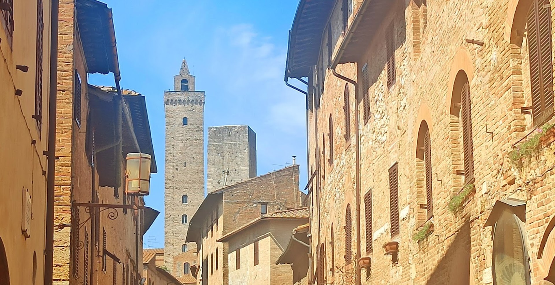 Via in mattoni del centro storico di San Gimignano con le torri medievali sullo sfondo