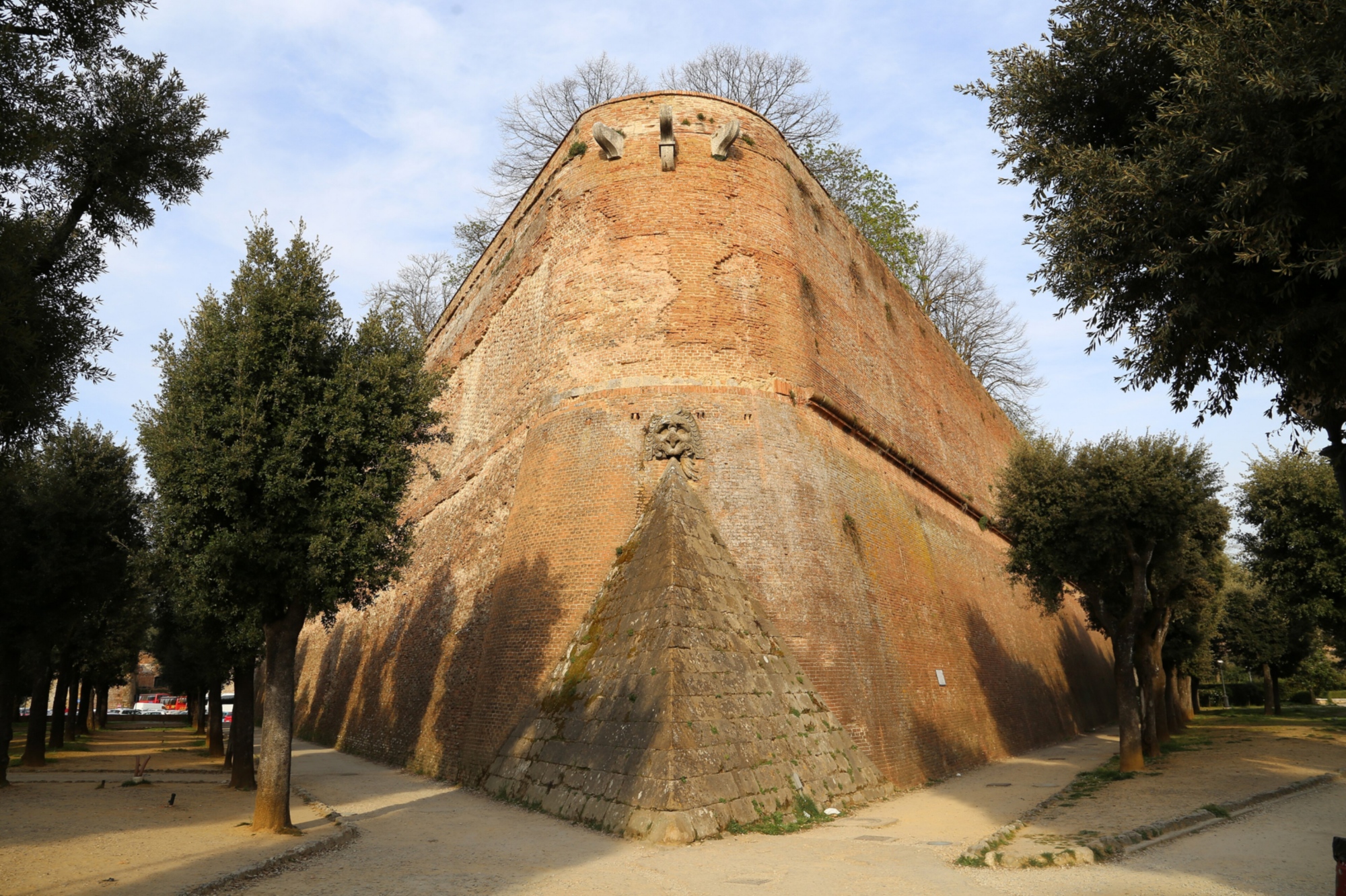 A close-up from below of the imposing spur-shaped corner of the western bastion of the Medici Fortress in Siena, built in red brick.