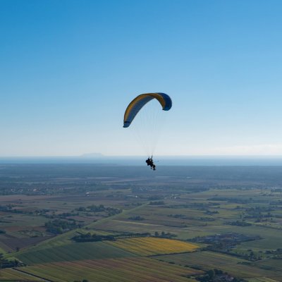 paraglider flying over the countryside with the sea on the horizon