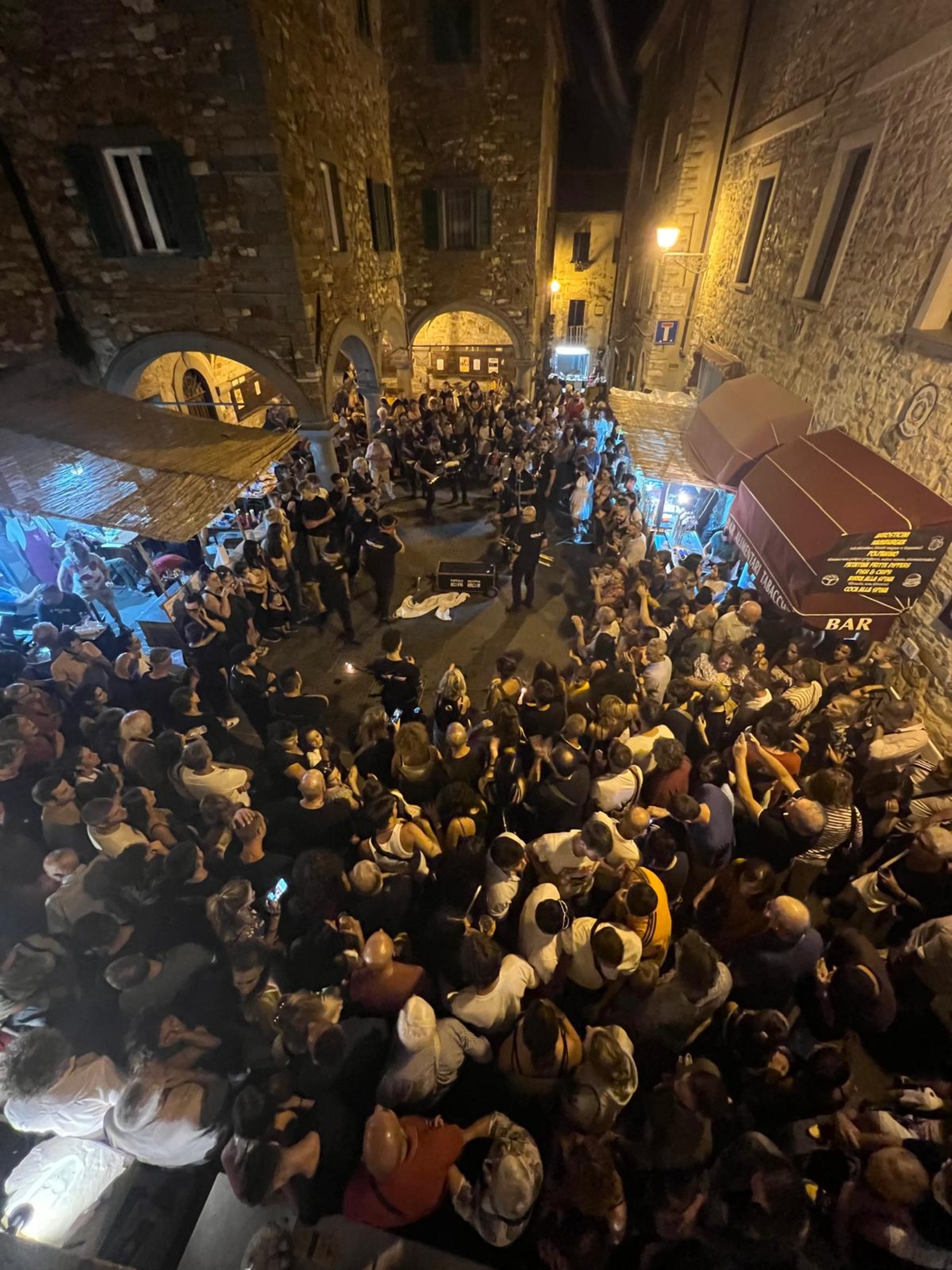 Immagine serale del festival con il pubblico riunito in piazza durante uno spettacolo musicale
