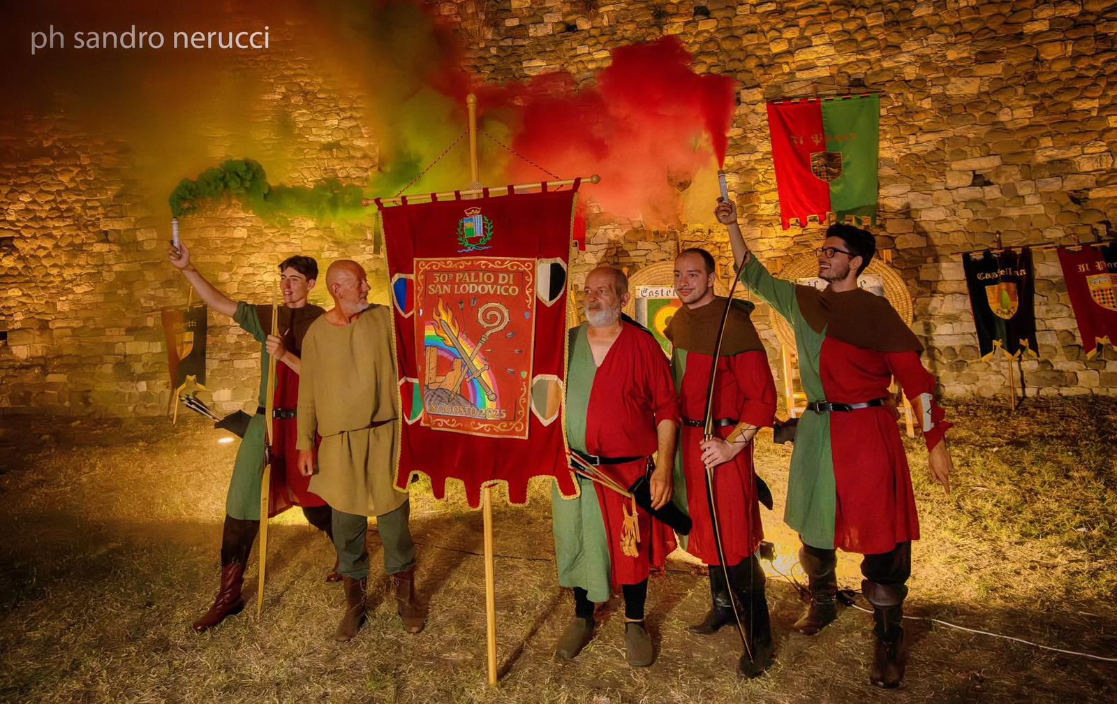Figuranti in costume medievale mostrano il Cencio del Palio di San Lodovico tra fumogeni colorati.