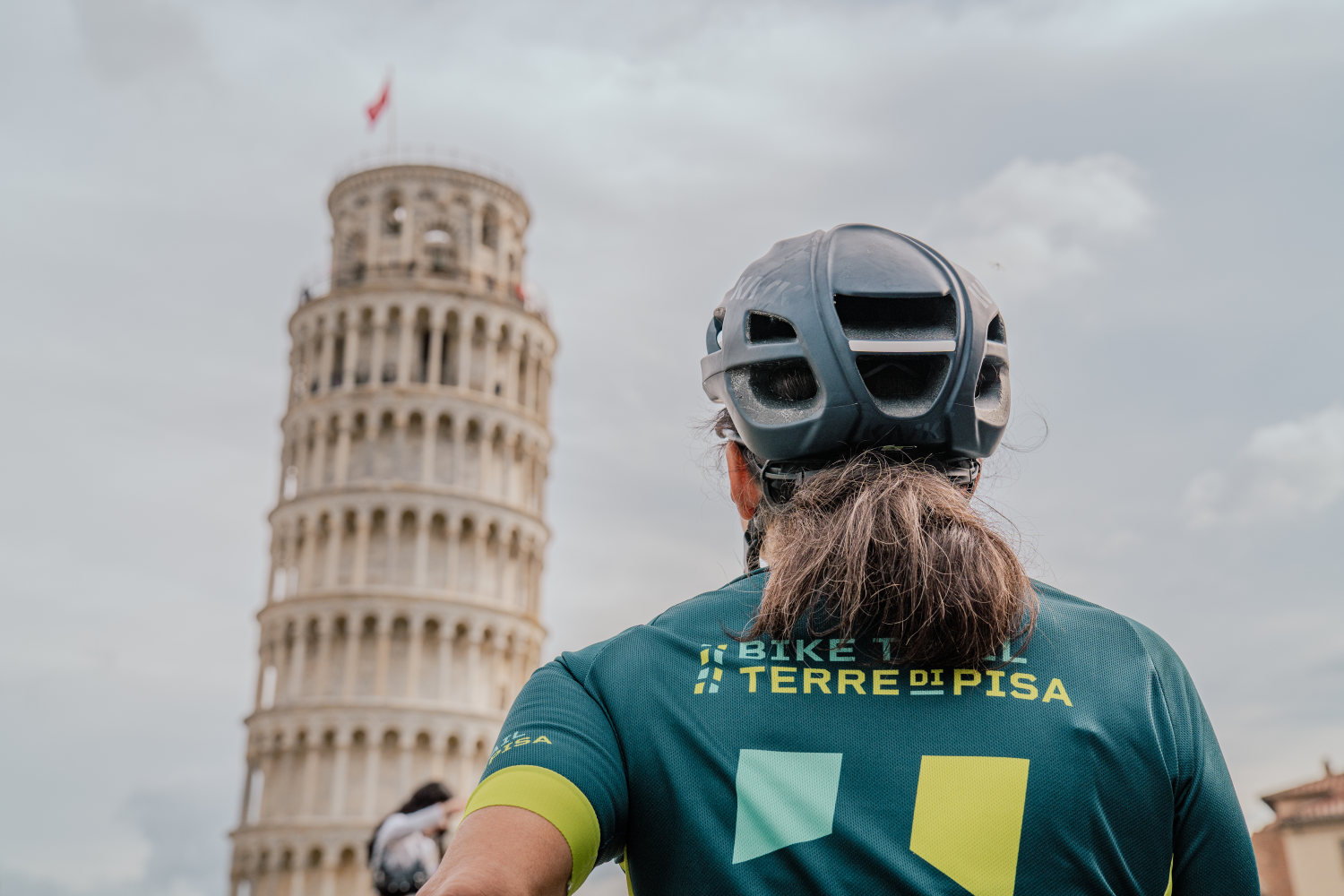 Un cycliste regarde la Tour penchée sur la Piazza dei Miracoli, point de départ idéal pour la piste cyclable permanente Terre di Pisa Bike Trail.