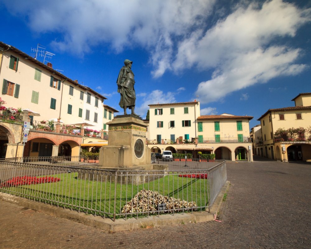 Die Piazza von Greve, umgeben von Bogengängen und der Giovanni da Verrazzano gewidmeten Statue im Zentrum