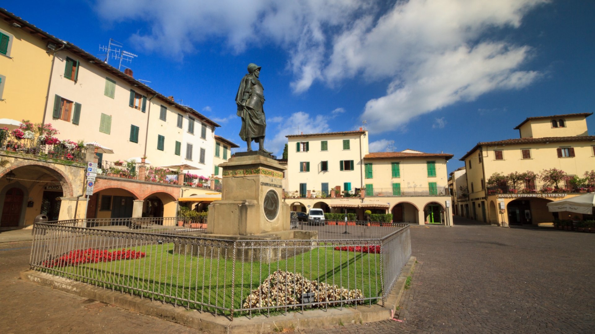 La grande place de Greve, entourée de portiques et avec la statue dédiée à Giovanni da Verrazzano au centre.
