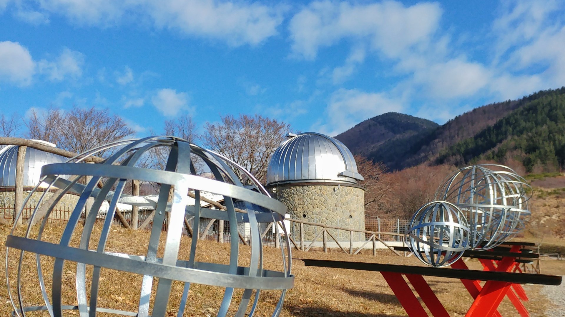 Some of the manufactured sculptures of the Stars Park representing the planets and, in the distance, the Pistoia Mountains Astronomical Observatory.