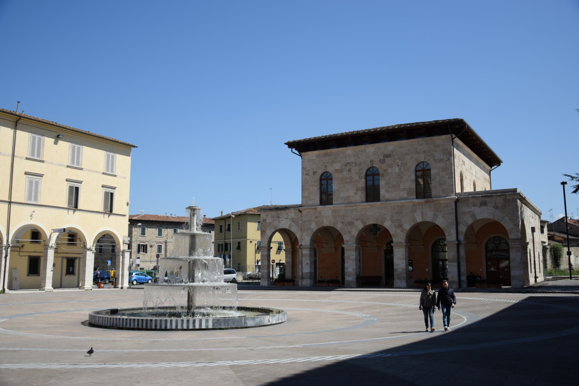Stazione di Colle Val d'Elsa in piazza con fontana e due passanti