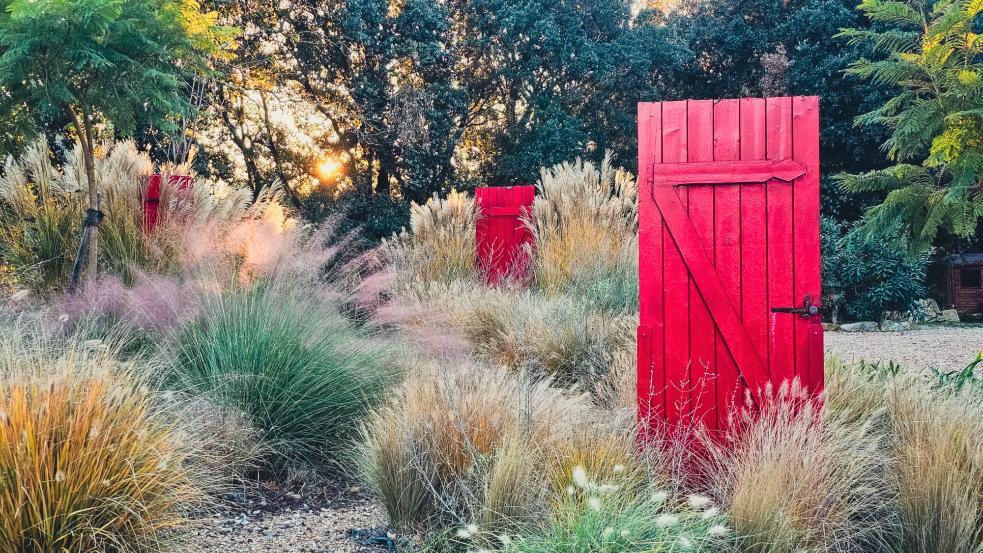 Le aiuole labirintiche con le sue graminacee svettanti. Al centro, 3 totem scultorei realizzati attraverso il recupero di antiche porte del casale.